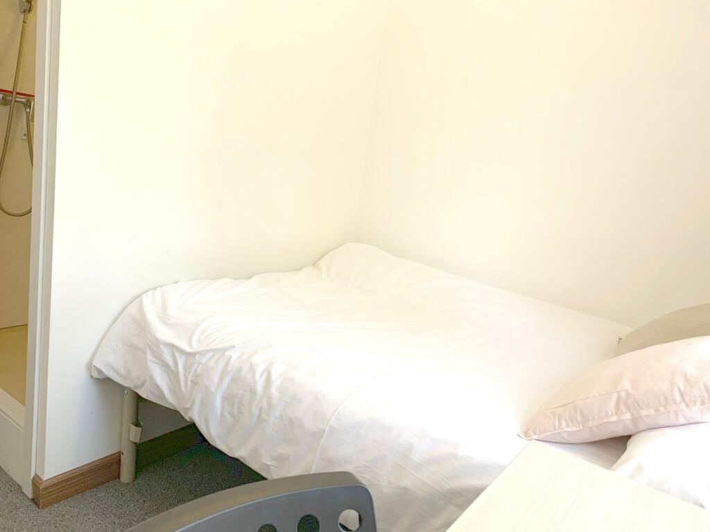 A cozy single bedroom featuring a neatly made b...