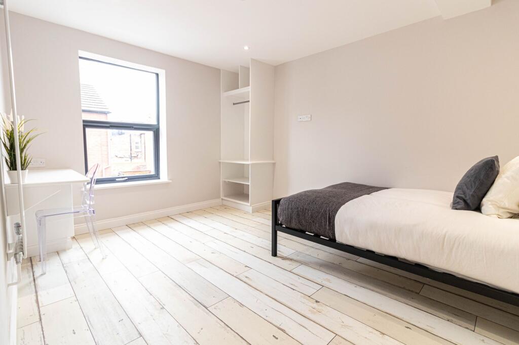 Bright, stylish bedroom with pale distressed wo...