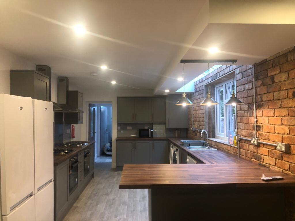 Modern fitted kitchen with a long wooden breakf...