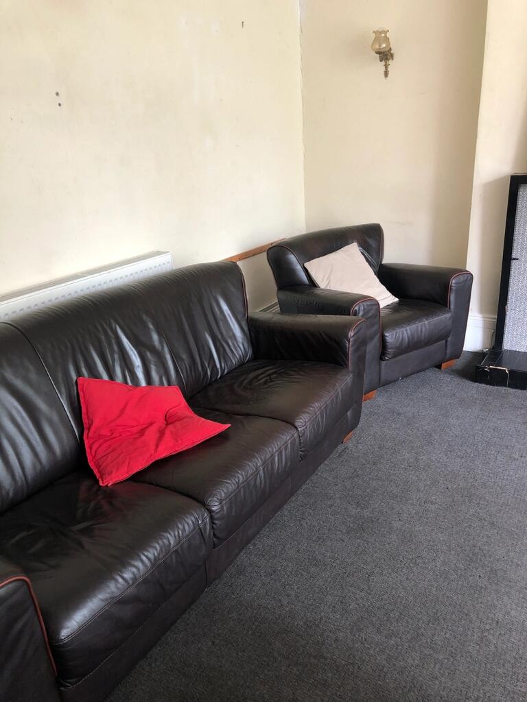 A tidy but dimly lit living room with a brown l...