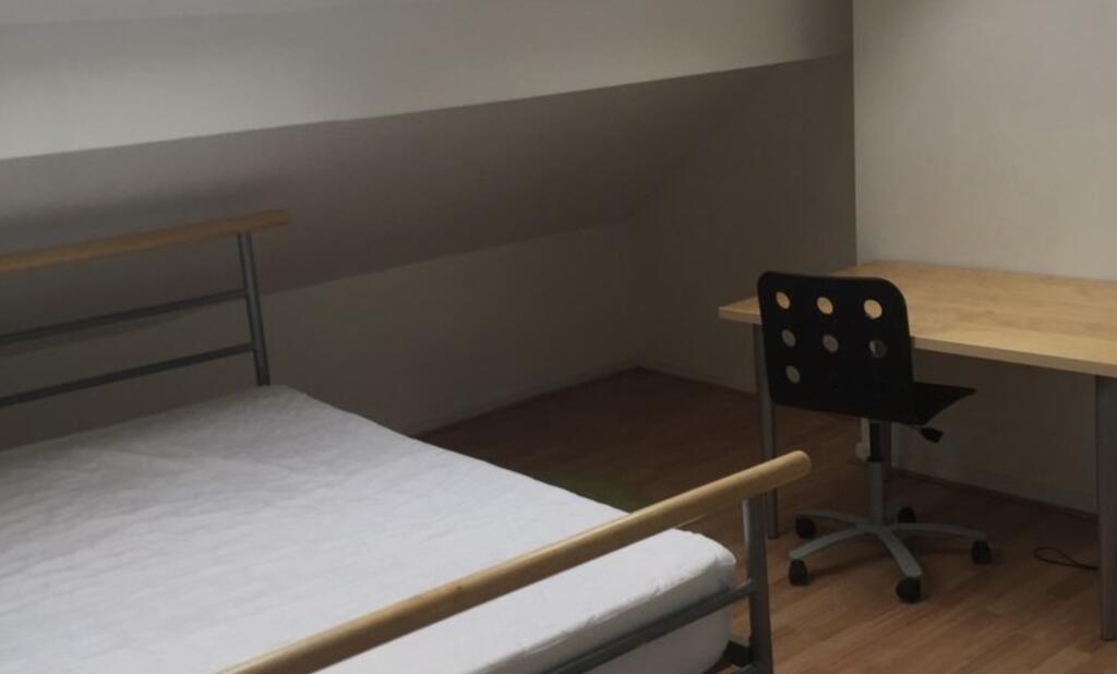 Neat attic-style bedroom with a simple metal-fr...