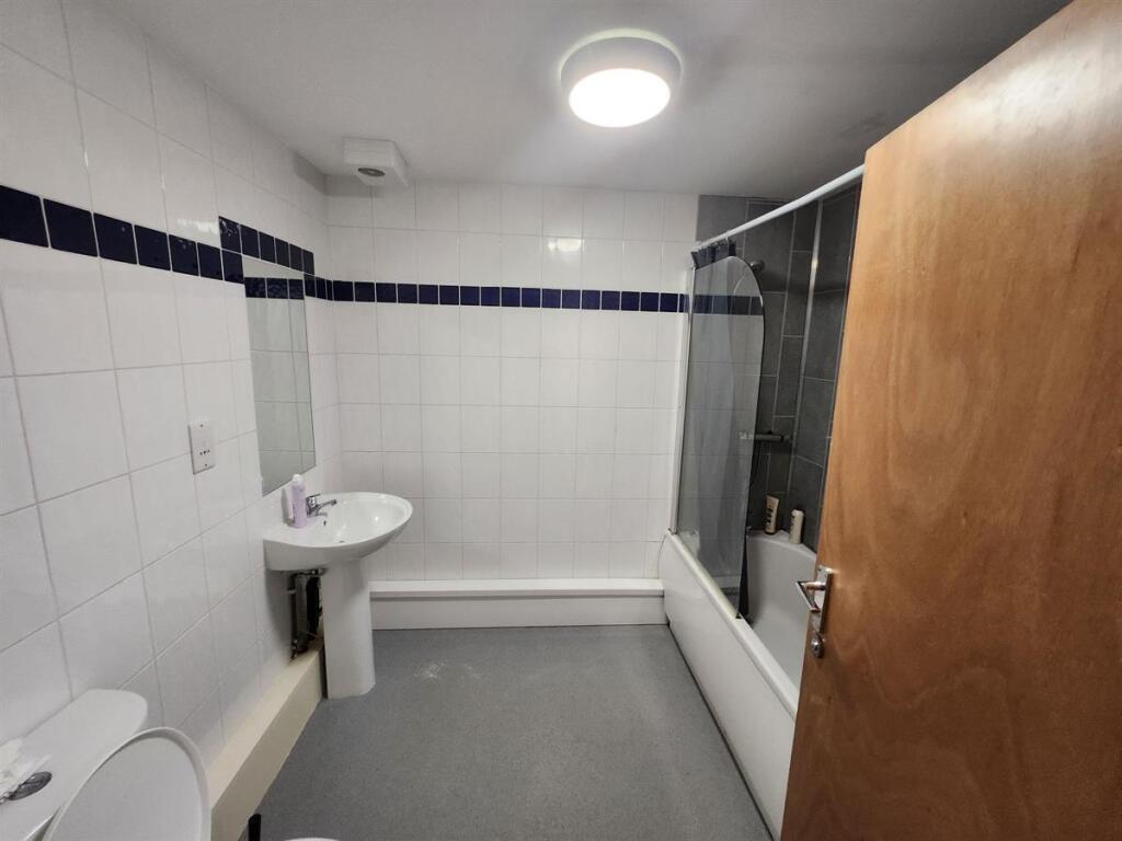 A clean and modern bathroom with a bathtub, sin...