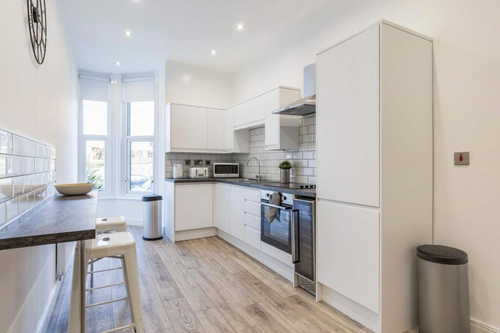 Bright modern kitchen with white cabinetry, int...