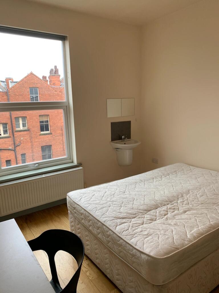 A bright double bedroom featuring a large windo...