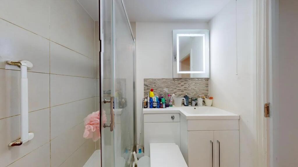 A modern bathroom suite featuring a glass-enclo...