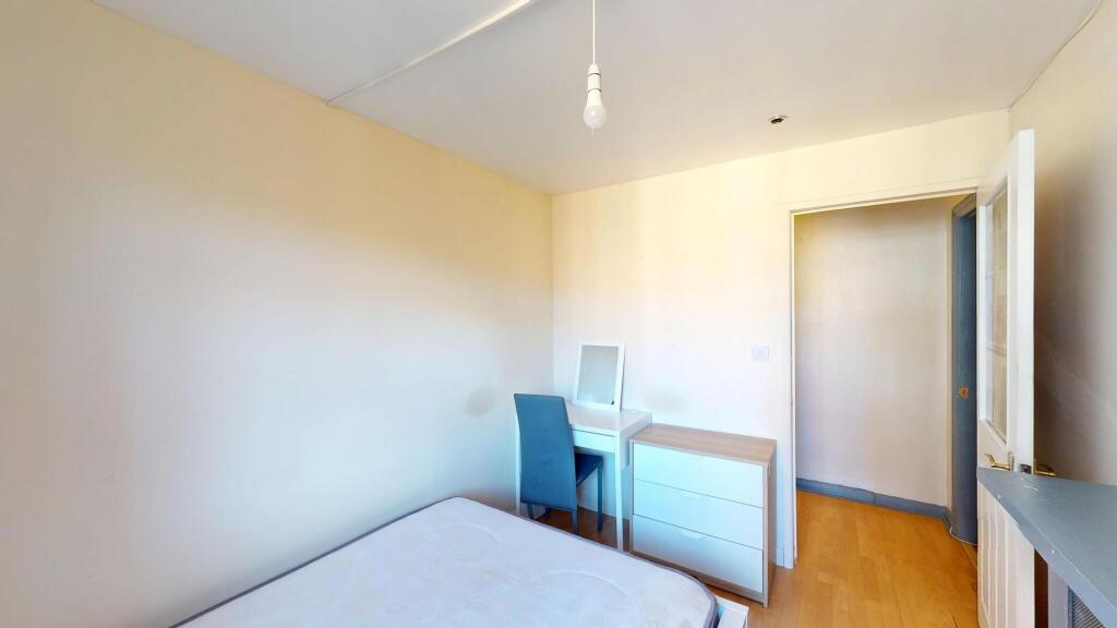 A bright and tidy bedroom featuring a bed, a sm...