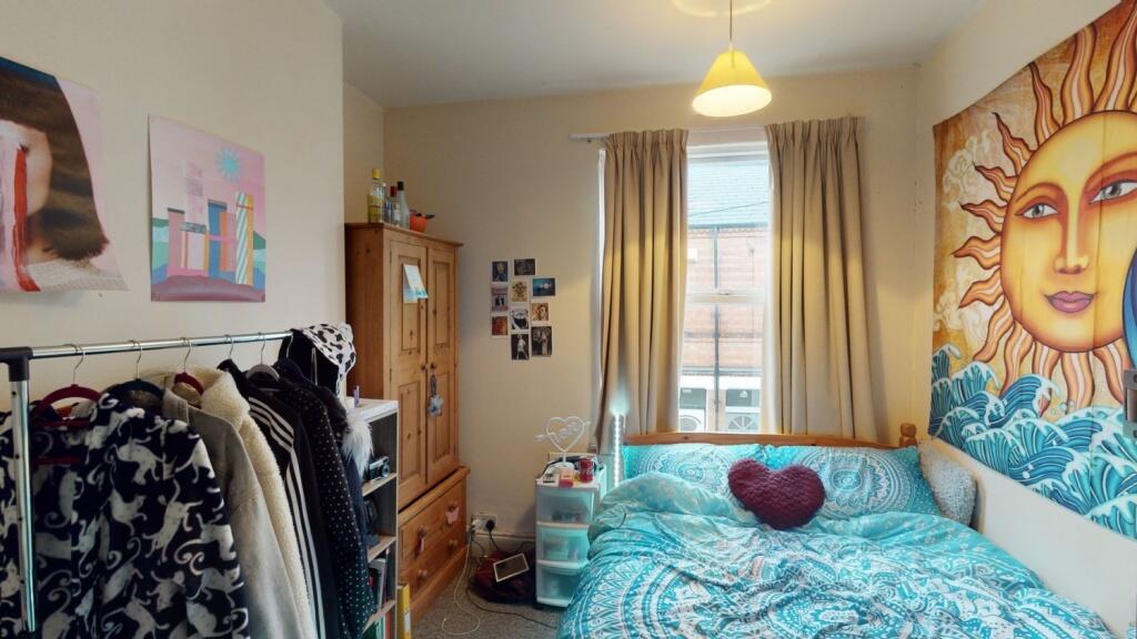 A cozy bedroom with a vibrant sun-themed mural ...