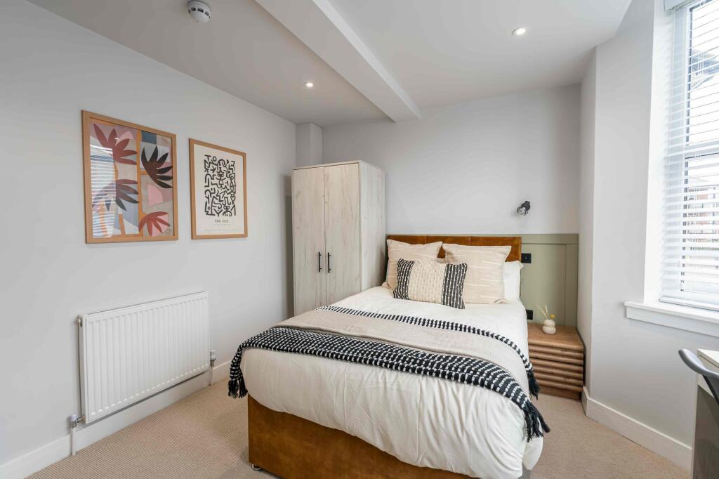 A bright and neatly arranged bedroom featuring ...