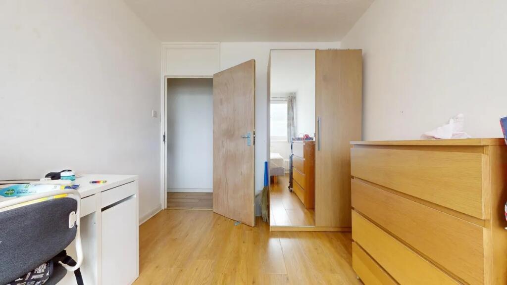 A tidy single bedroom featuring wooden flooring...