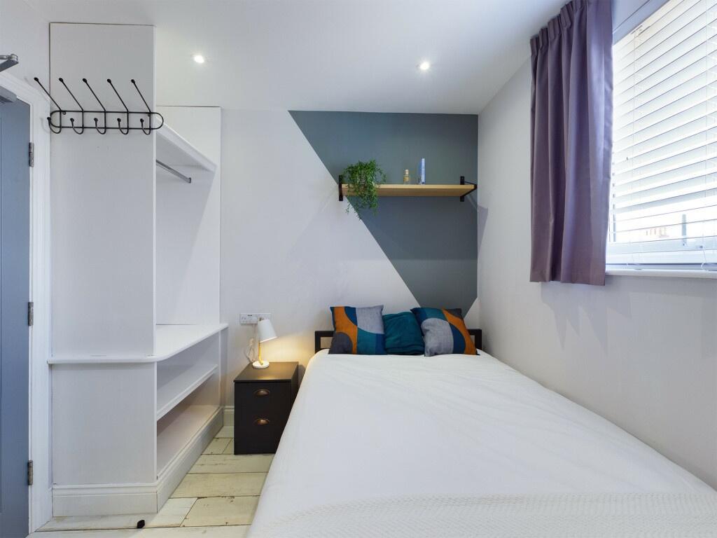 A bright and clean single bedroom featuring a c...