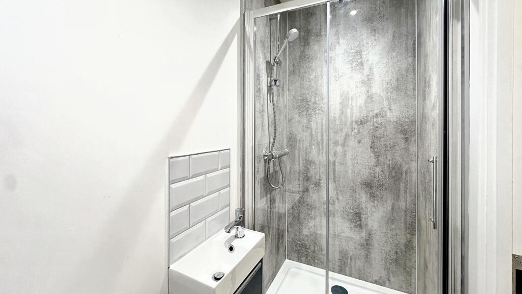 Modern bathroom featuring a sleek glass shower,...