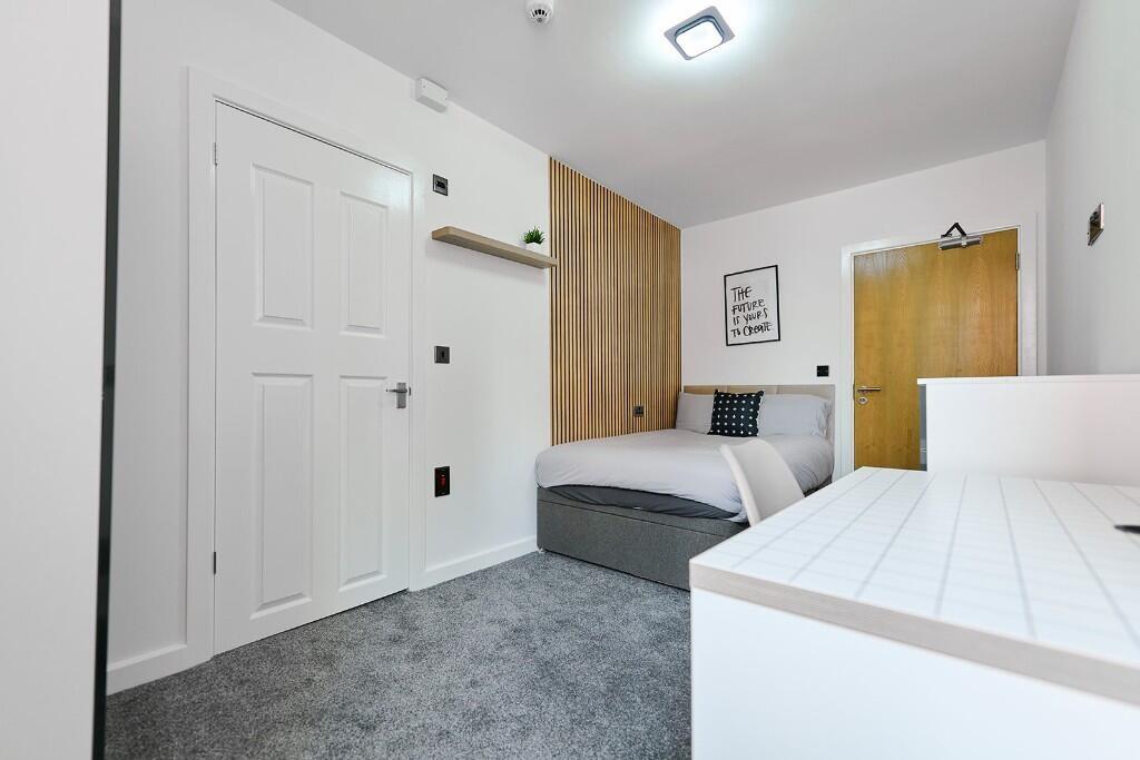 A neat and modern single bedroom with a cozy be...