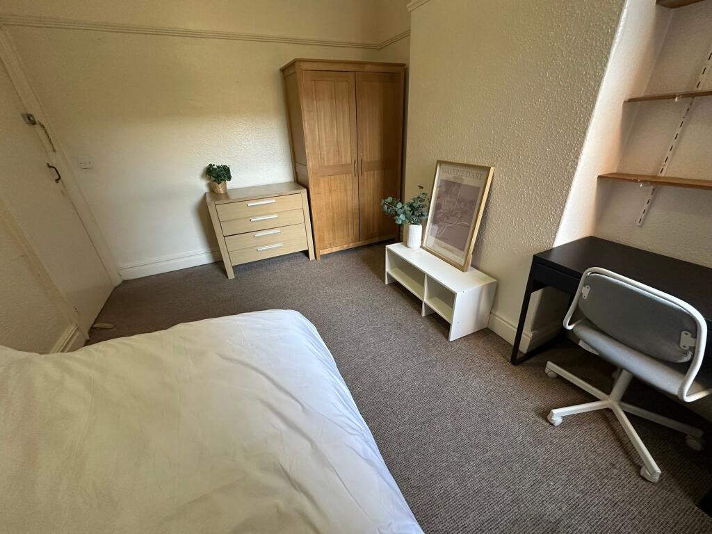 A cozy single bedroom featuring a neatly made b...