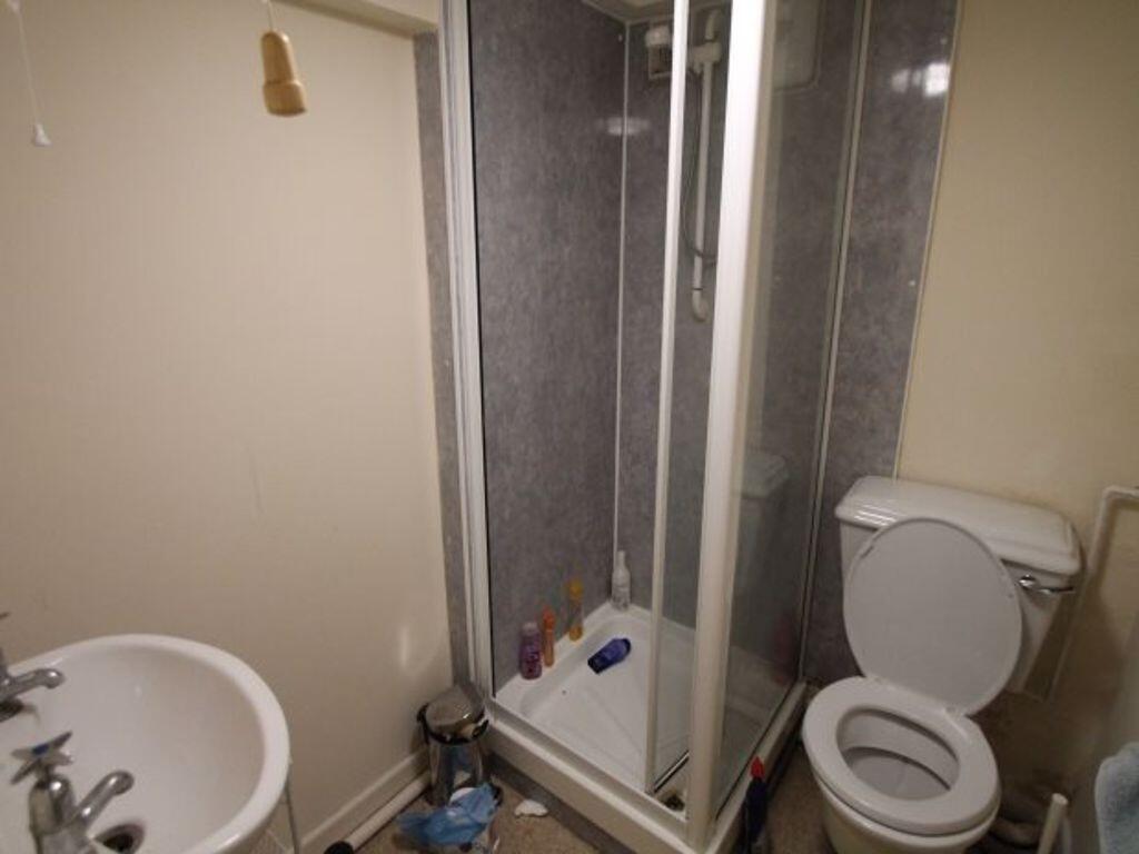 A compact bathroom featuring a corner shower un...