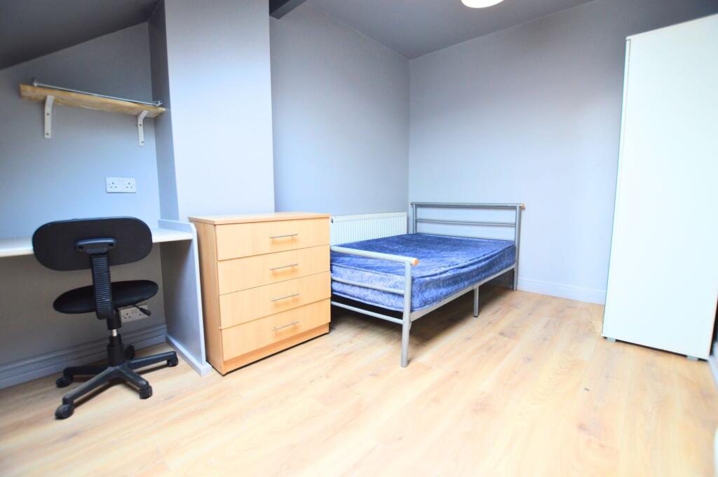 A tidy single bedroom featuring a wooden floor,...