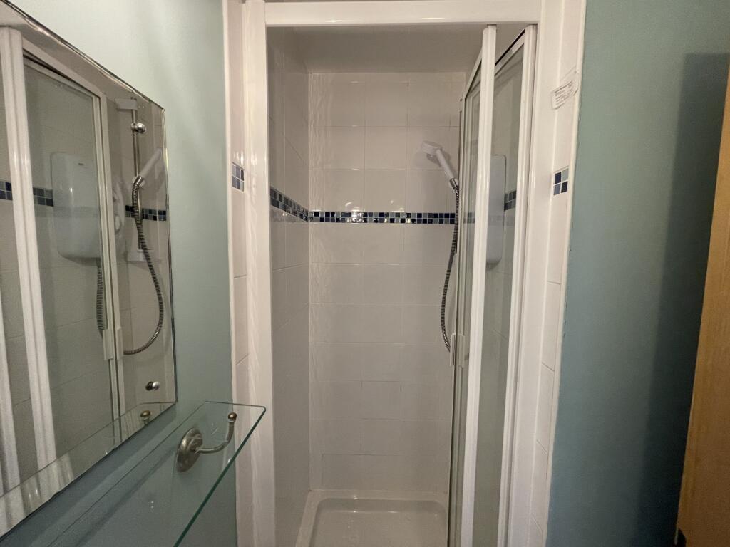 Compact bathroom featuring a tiled shower enclo...