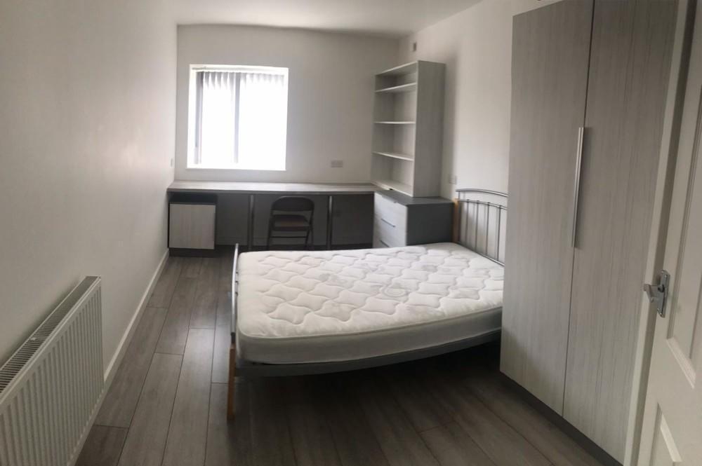 A neat and uncluttered single bedroom featuring...