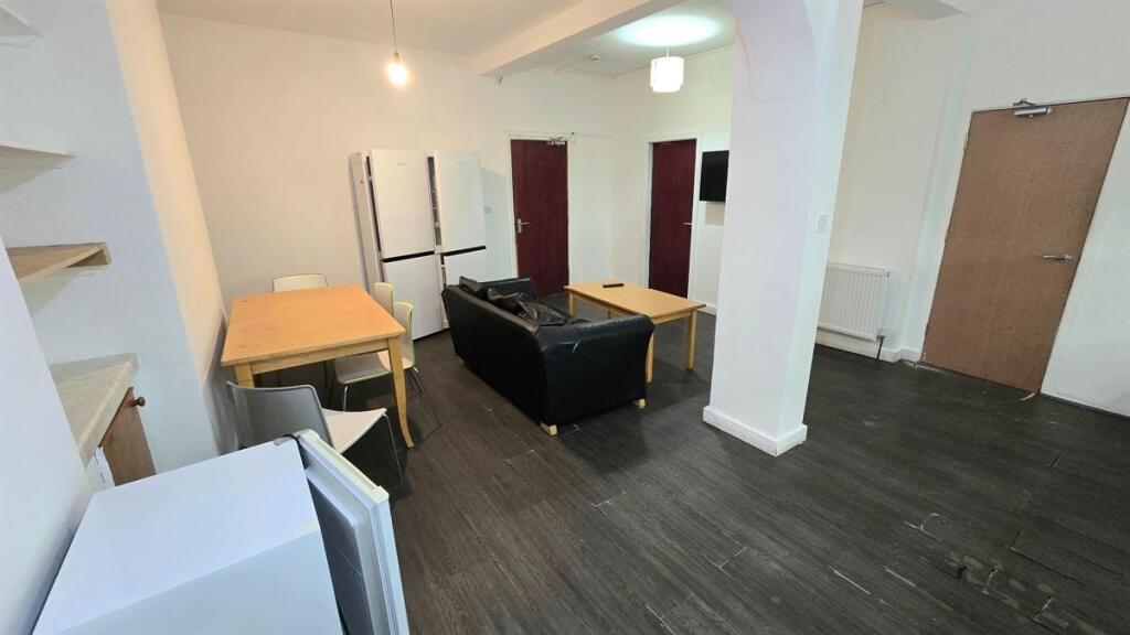 Open-plan living area with modern dark wood flo...