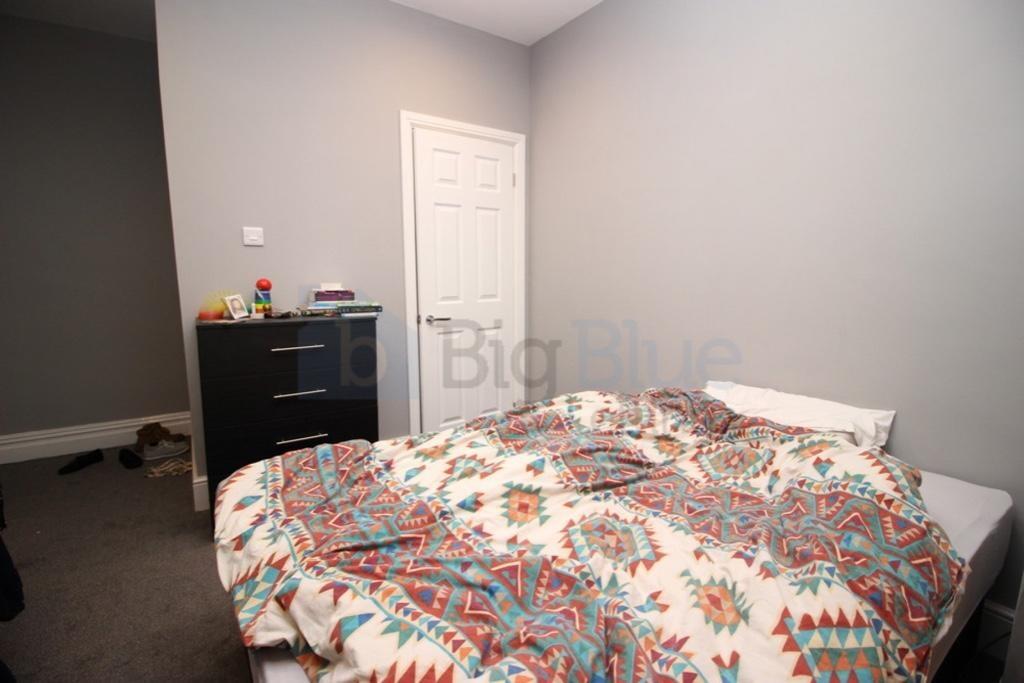 A cozy double bedroom featuring a patterned bed...