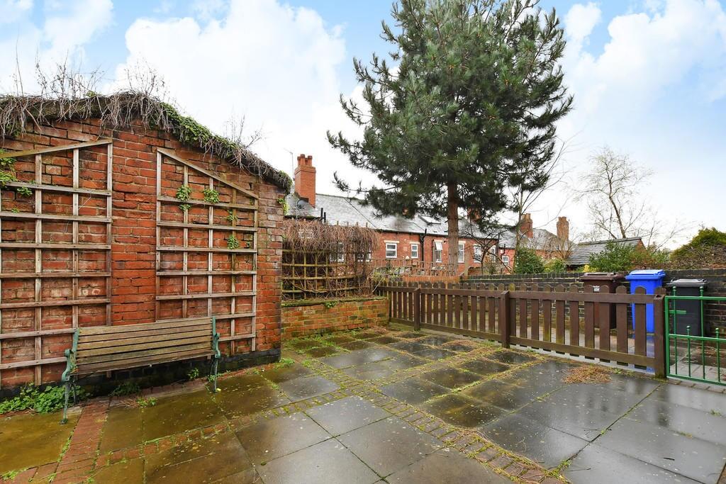 Spacious paved garden area with seating bench a...