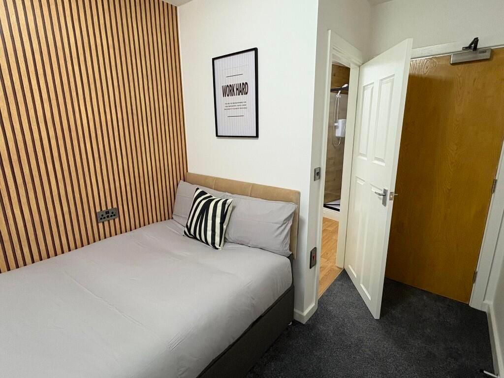 A cozy and tidy single bedroom featuring a comf...