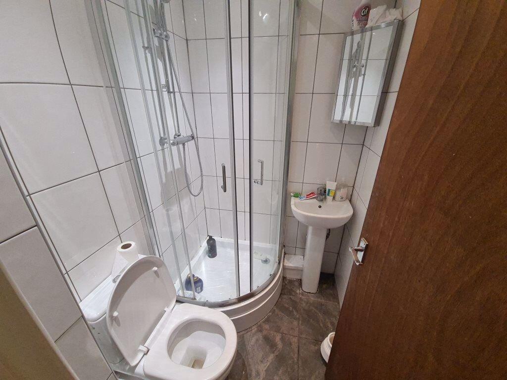 Bright tiled bathroom with a corner glass showe...