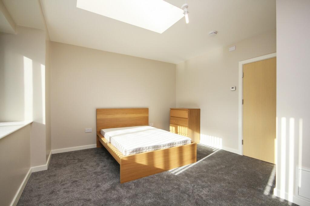 A bright and spacious double bedroom with moder...