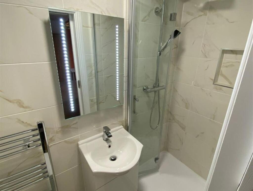 A modern, clean bathroom featuring a shower wit...
