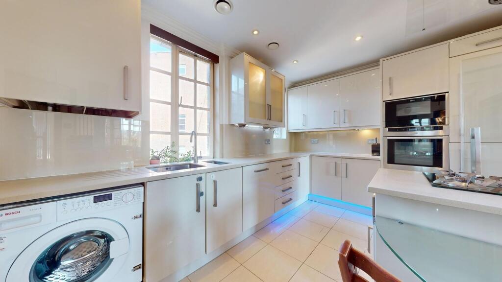 Modern kitchen featuring sleek white cabinetry,...