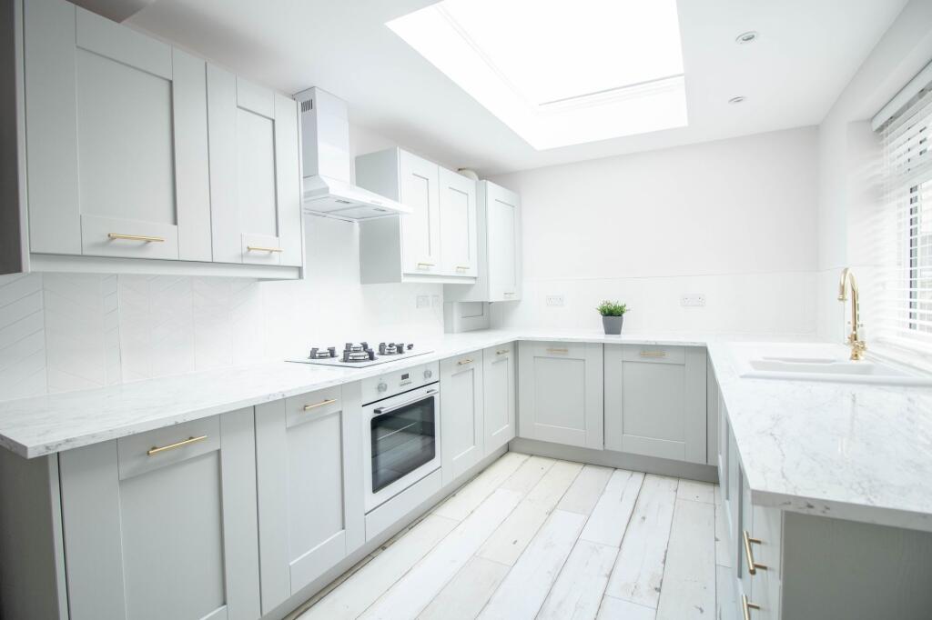 Bright and modern kitchen with white cabinetry,...
