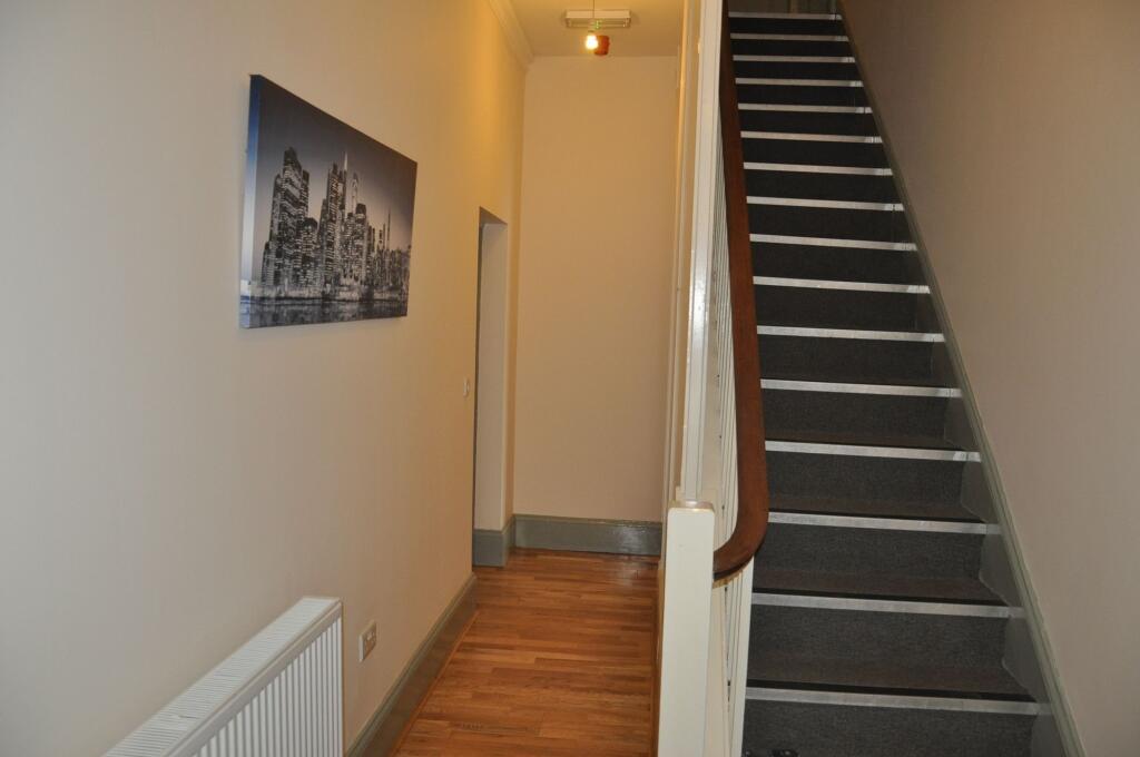 A clean and tidy hallway featuring wooden floor...