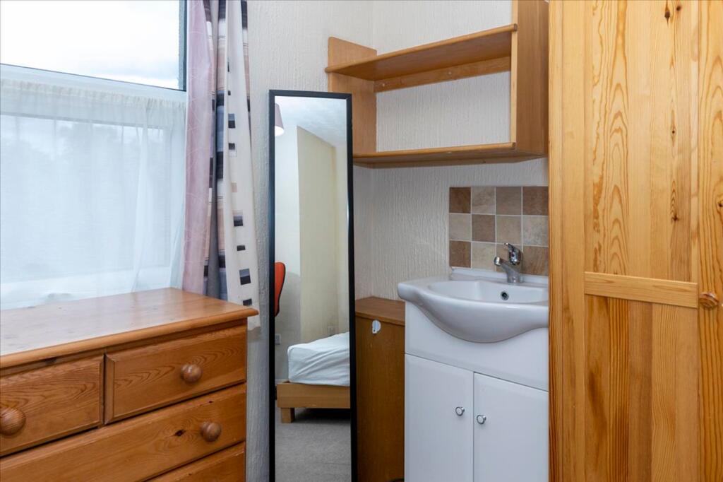 A cozy double bedroom featuring a stylish woode...