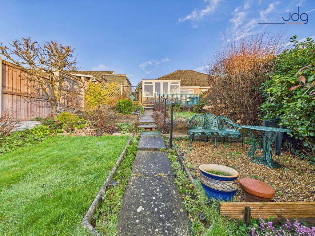 A generous, tiered rear garden with paved seating areas and lawn