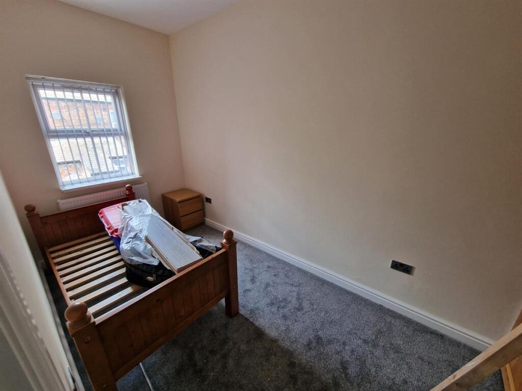 Cozy single bedroom featuring a wooden bed fram...