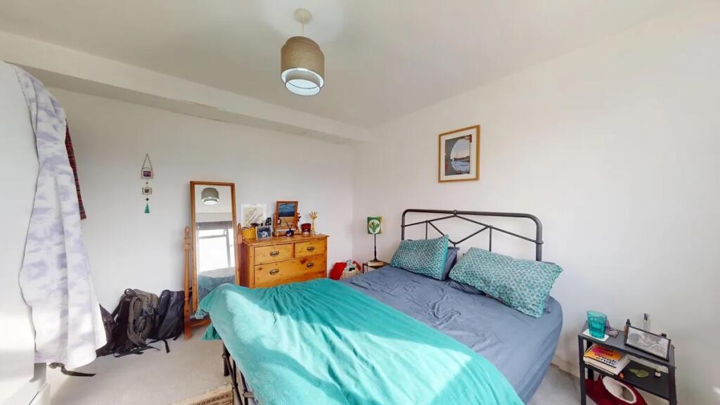 Bright double bedroom featuring a cozy metal be...
