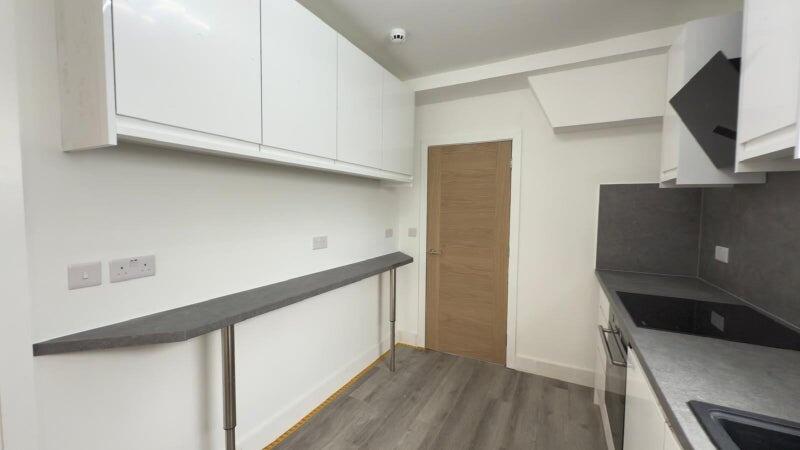 Modern kitchen with sleek white cabinets and da...