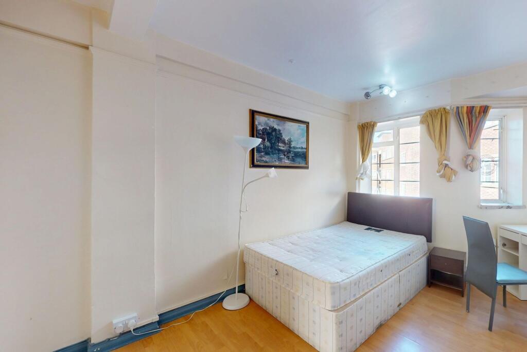 A compact bedroom featuring a single bed, a sid...