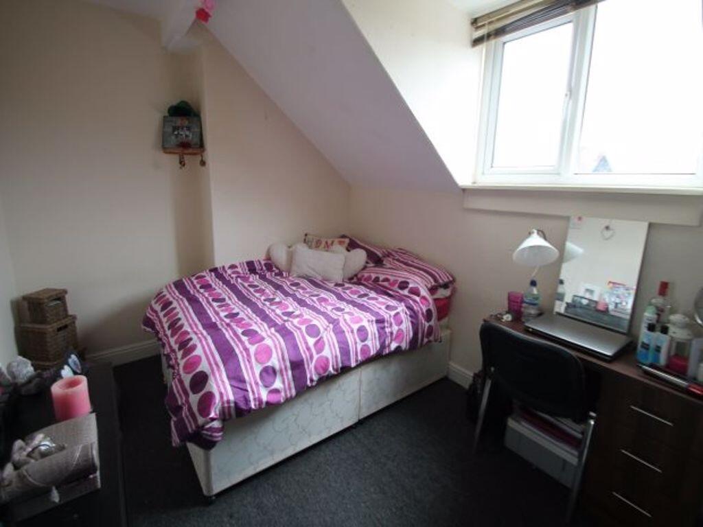 A cozy single bedroom with a sloped roof, featu...