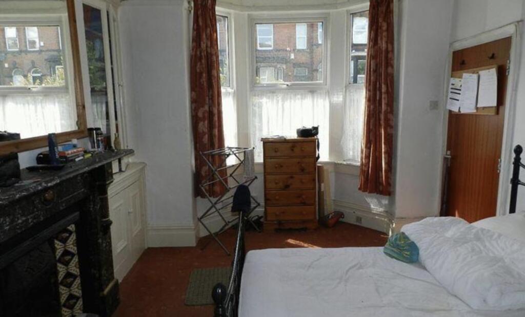 A bright, tidy bedroom with two large windows p...