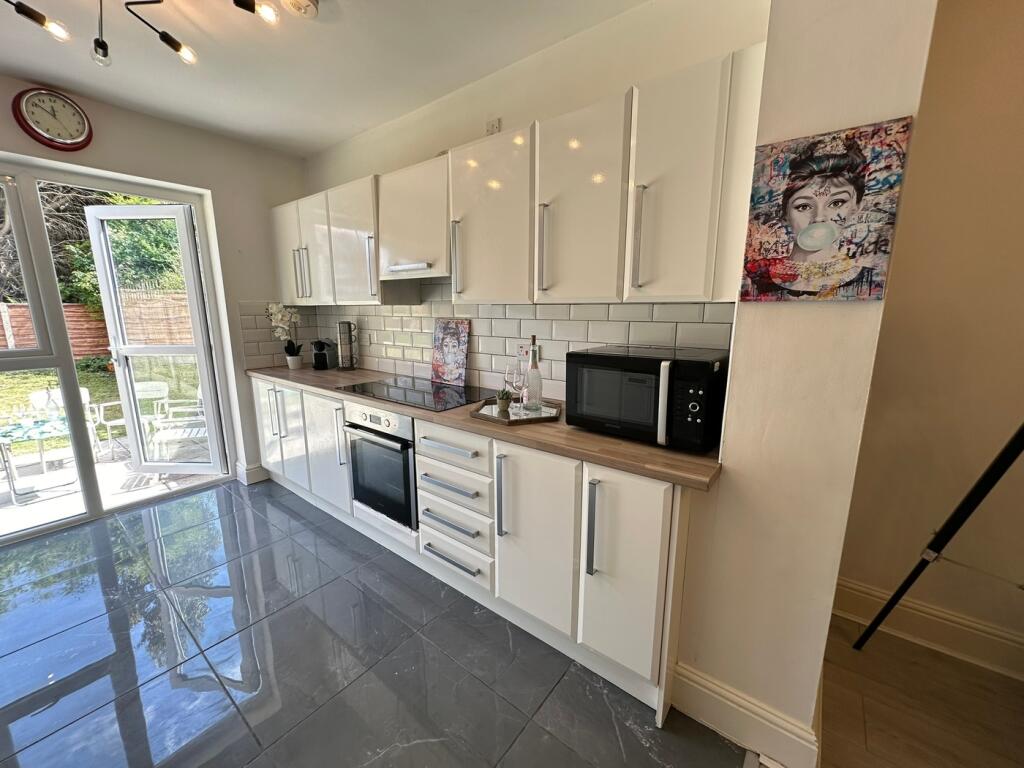 This modern kitchen features sleek white cabine...