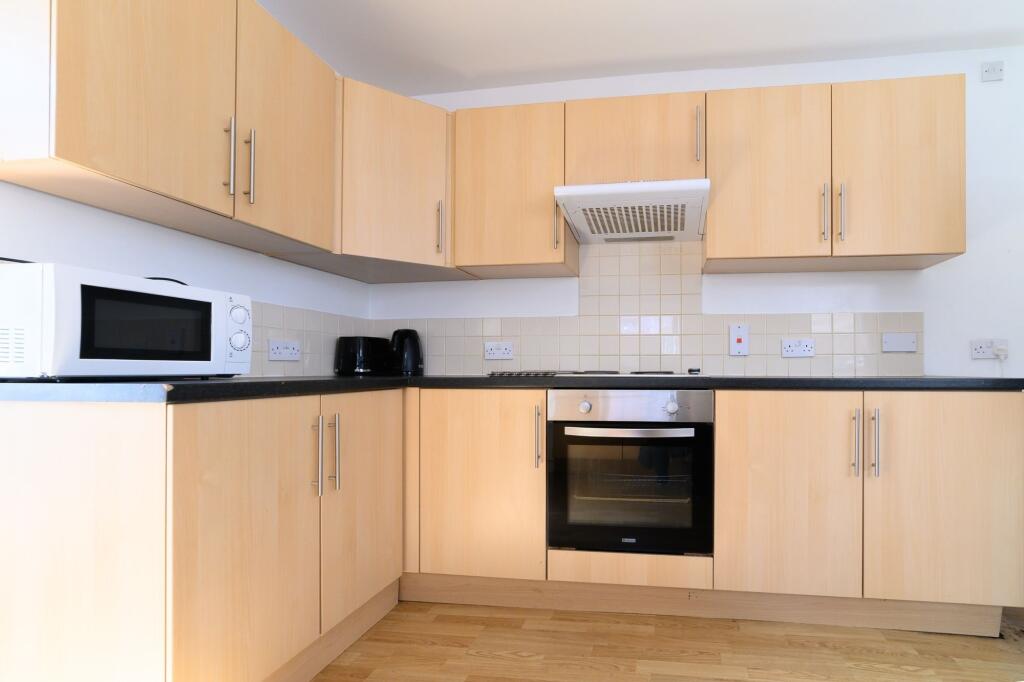 A modern, clean kitchen featuring wooden cabine...