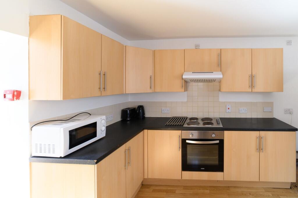 Modern kitchen with light wood cabinets, a micr...
