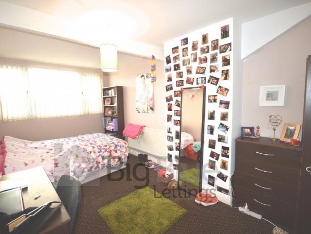 Cozy single bedroom featuring a bed with floral...