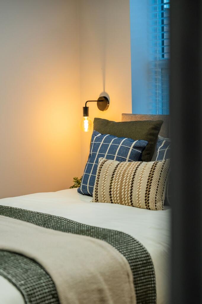 Stylish double bedroom with layered cushions, w...