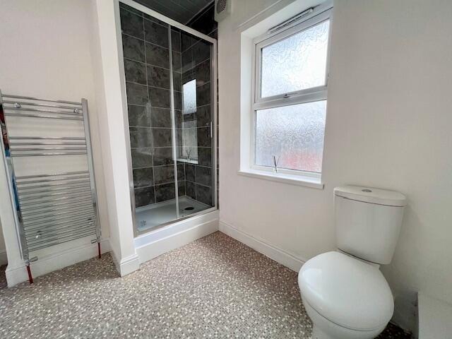 A clean, modern bathroom featuring a walk-in sh...