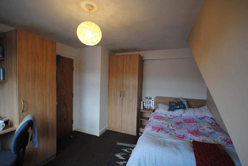 A well-lit double bedroom featuring a comfortab...