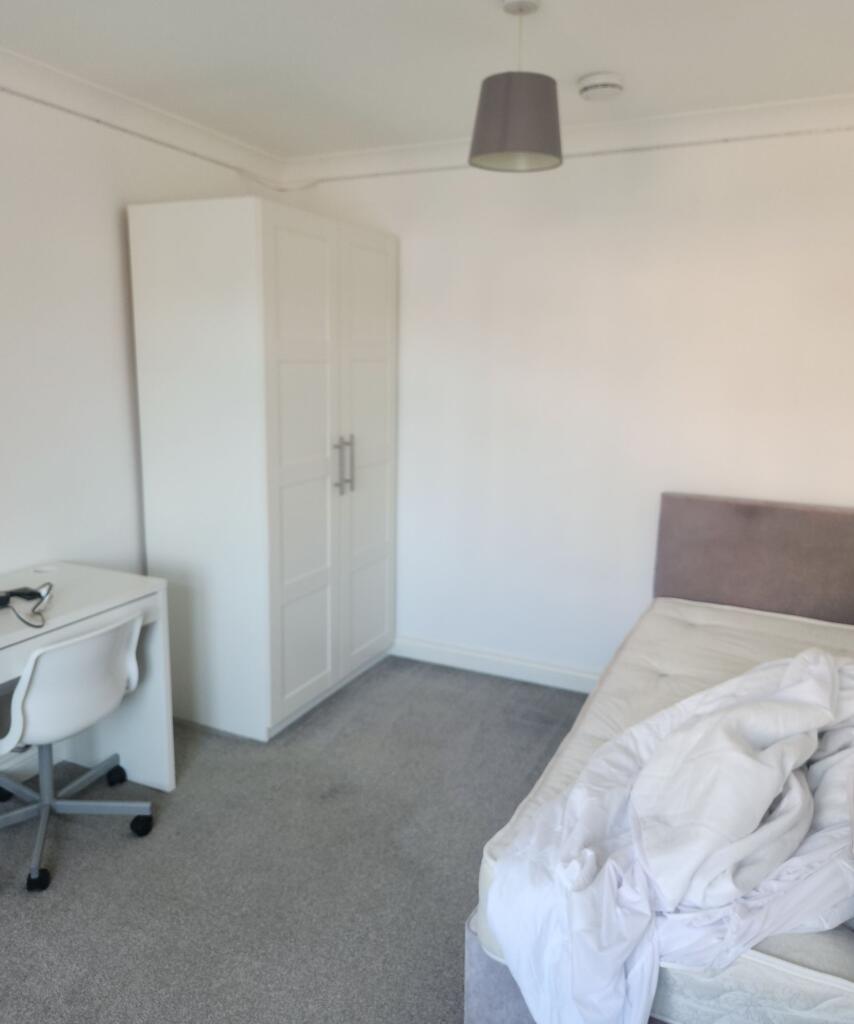 A tidy bedroom featuring a wardrobe, a bed with...