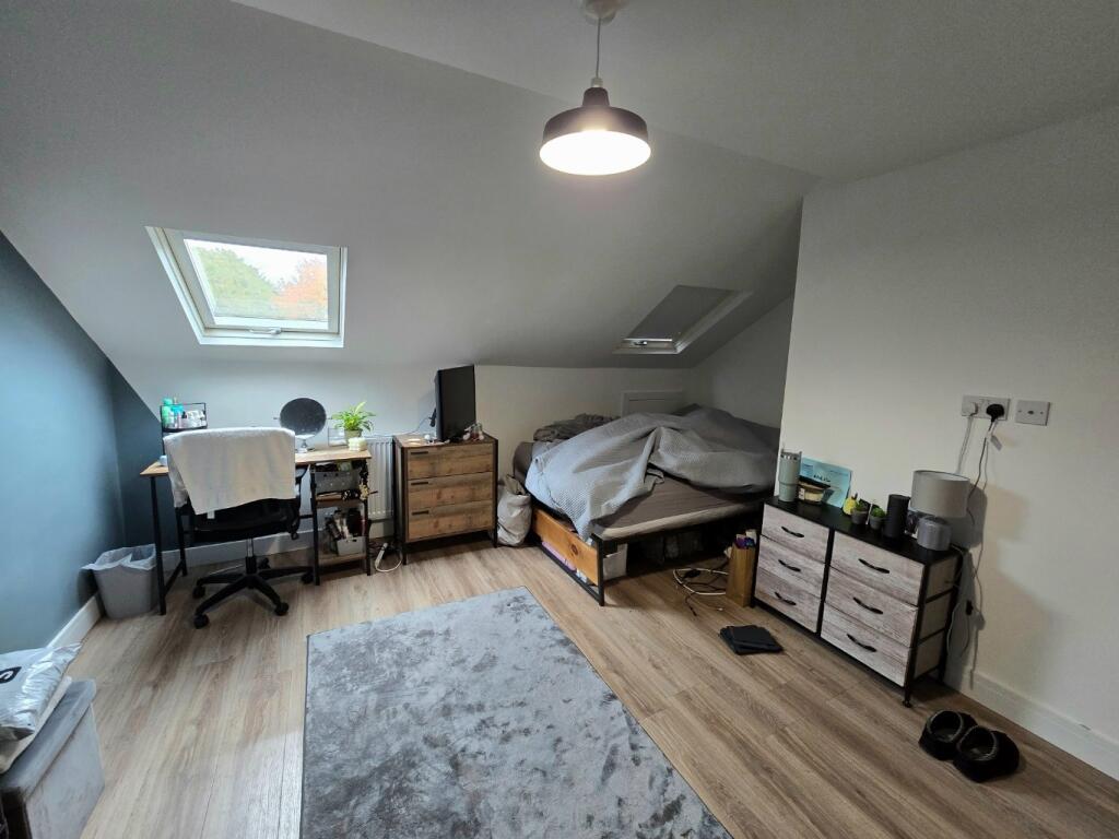 A well-lit bedroom with a comfortable bed, desk...