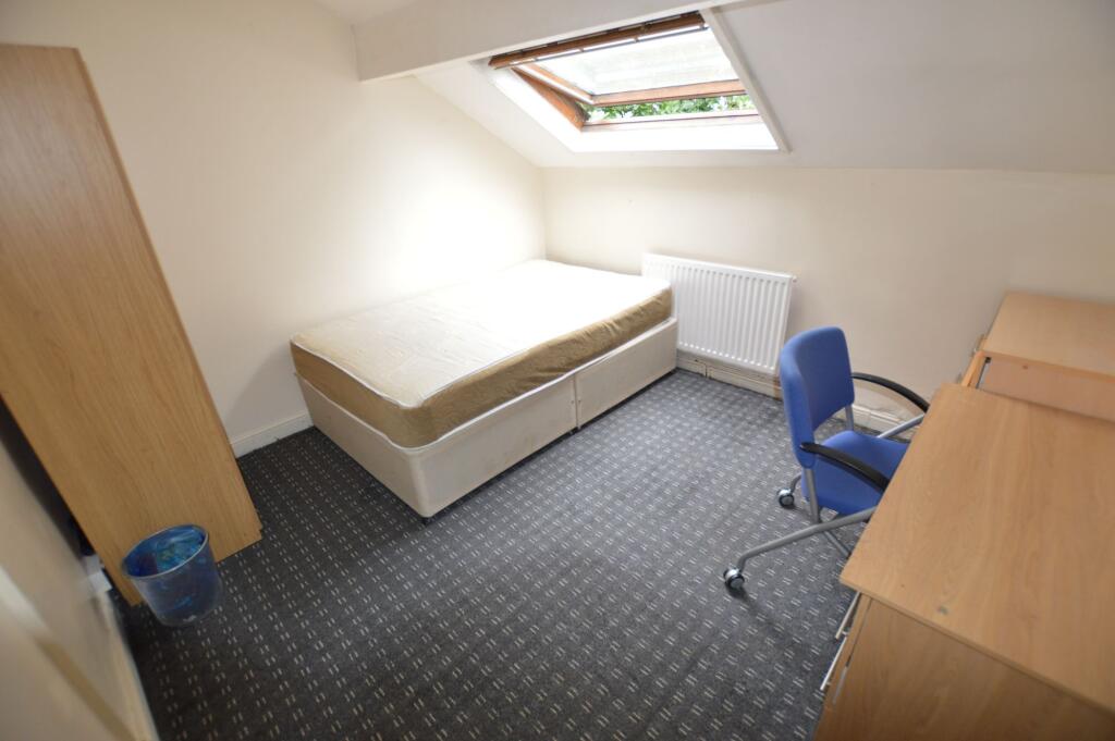 A cozy single bedroom with a large skylight win...