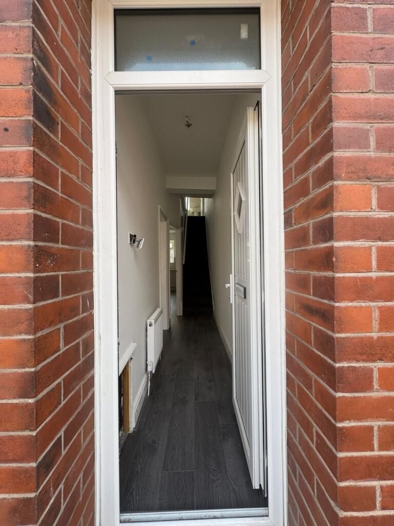 A narrow, clean hallway with dark flooring and ...